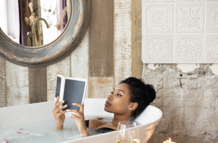 Jeune femme noire lisant un livre dans son bain.